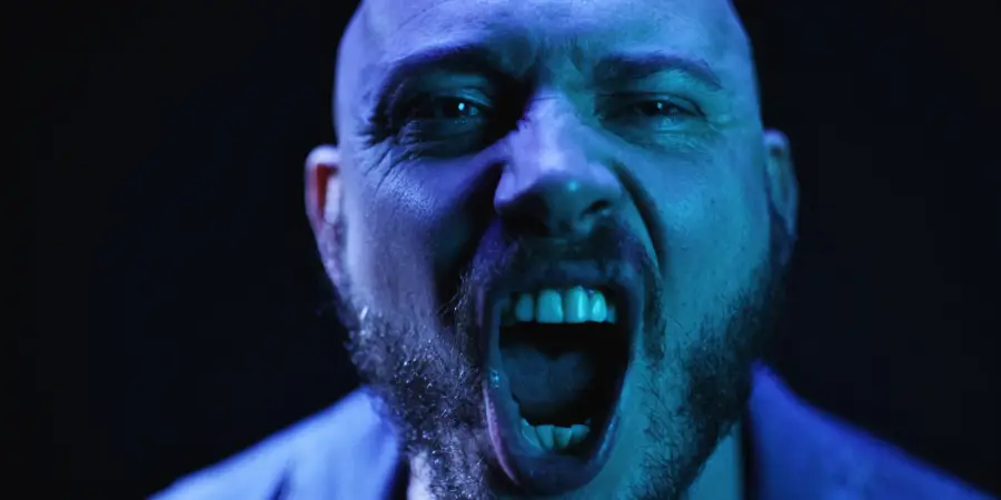 Box of Rules: blue-lit close-up, screaming into camera