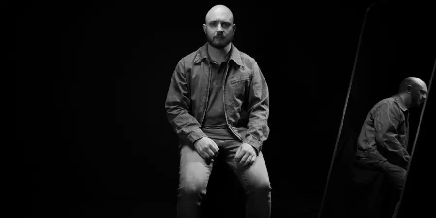 Box of Rules: black-and-white seated portrait beside a mirror